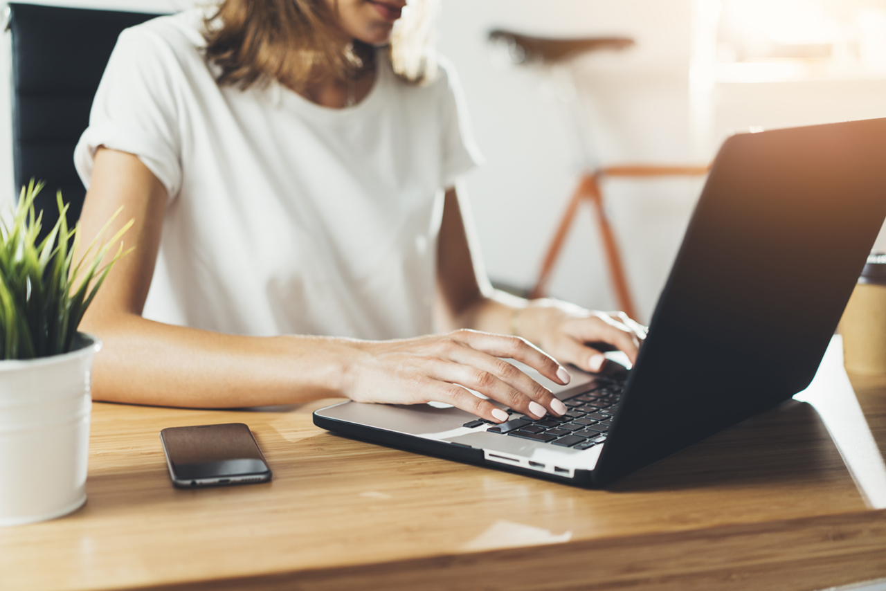 Close-up image of young professional female manager using laptop at her office